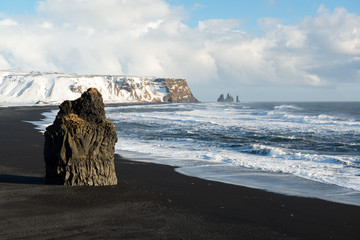 Winter landscape with Reynisdrangar stacks, mountain, black sand beach and ocean waves, Iceland