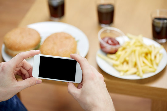 close up of man with smartphone picturing food