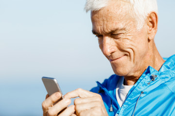 Male runner with his mobile smart phone standing outdoors