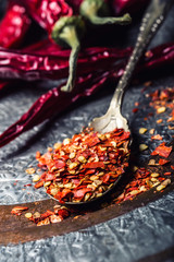 Chili. Chili peppers. Several dried chilli peppers and crushed peppers on an old spoon spilled around. Mexican ingredients - cuisine.