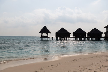 bungalow huts in sea water on exotic resort beach