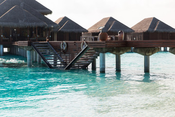 bungalow huts in sea water on exotic resort beach