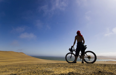 Fototapeta na wymiar man standing with bicycle looking to ocean