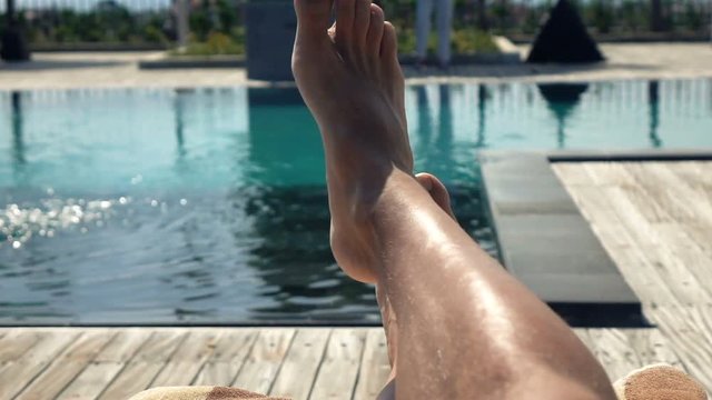 Male feet on daybed by swimming pool, super slow motion 240fps
