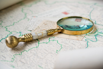 Old beautiful golden magnify glass on ancient post cards and old map