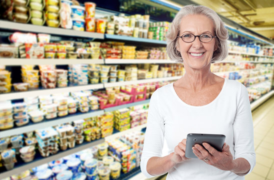 Senior woman using tablet pc in supermarket