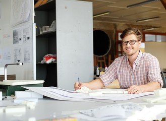 Young architect working on drawing table in architect studio.