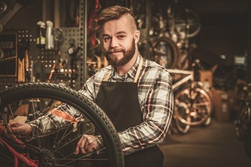 Fototapeta na wymiar Stylish bicycle mechanic doing his professional work in workshop.