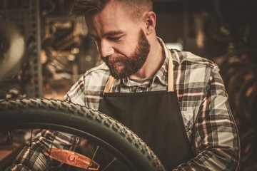 Obraz na płótnie Canvas Stylish bicycle mechanic doing his professional work in workshop.