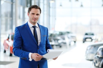 Fototapeta premium Confident young car dealer standing in showroom.