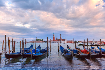 Fototapeta na wymiar Gondolas moored by Saint Mark square with San Giorgio di Maggiore church in the background during twilight blue hour, Venice, Italia