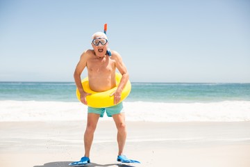 Senior man with swimming ring and flippers at the beach