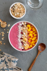 Strawberry smoothie bowl topped with mango, granola, pomegranate and shredded coconut