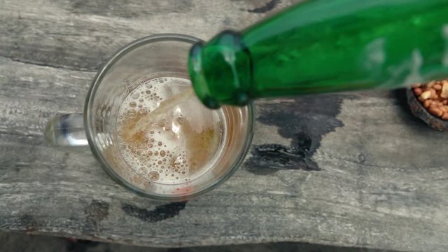 Pouring beer in glass on wooden table, super slow motion 240fps
