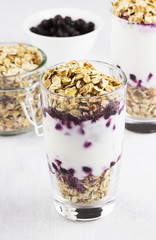 Useful dessert of granola, yogurt and blueberry in glass on a wh