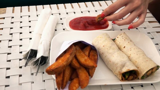 Woman dipping French fries in ketchup sauce, super slow motion 240fps
