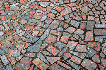 Pavement of polished natural stone fragments of red and gray color.