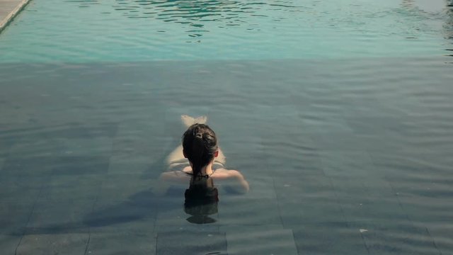 Young woman relaxing in swimming pool, super slow motion 240fps
