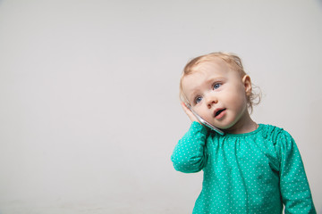 Cute little baby is talking on cell phone, isolated over white