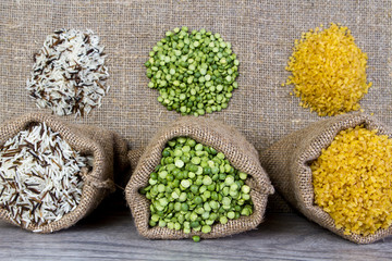 Set groats, peas, rice, millet, peas in sacks, burlap on wooden background