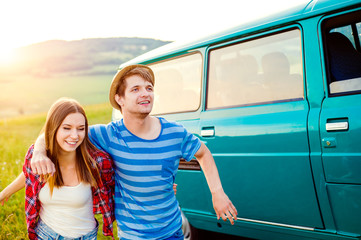 Teenage couple in love outside in nature, green campervan