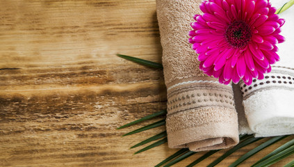 Spa setting with towels and pink flower on wooden background