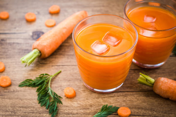 Carrot juice and carrot segments on a wooden background