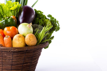 Variety of raw vegetables in basket isolated on white background
