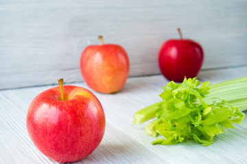 Apples and bunch of celery on a white table