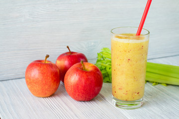 Smoothies made from apples and celery in a glass with a straw on