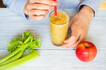 Female hands hold Smoothies from apples and celery in a glass wi