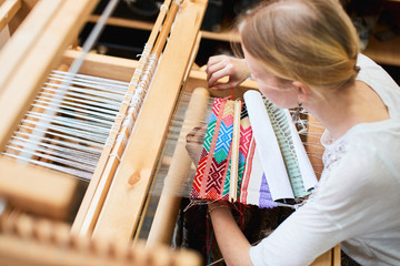 The girl in the production process of textiles are handmade on a loom