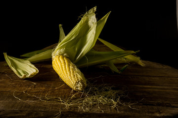 Fresh corn on the table, dark background.