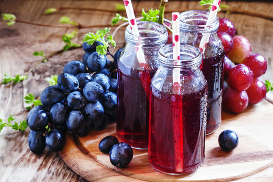 Juice from dark grapes in small glass bottles, selective focus