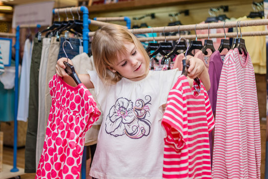 Little Girl Choose Clothes In Boutique. Shopping Day.