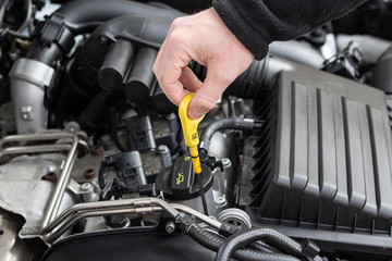 hand checking oil dip stick in modern car motor