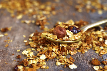 Granola on a spoon on rustic background.