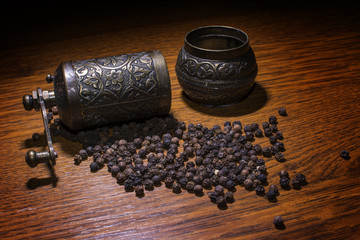 Pepper beans and grinder isolated on wood background 