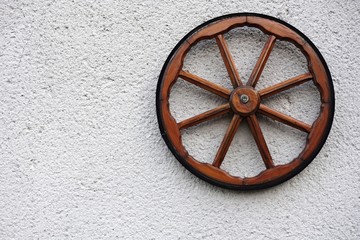 Old wooden wheel on a white wall
