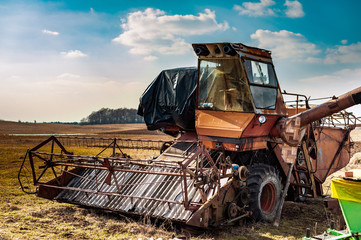Old rusty abandoned harvester on a country field