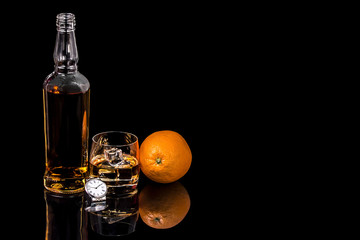 Bottle and glass whiskey with watch on black background