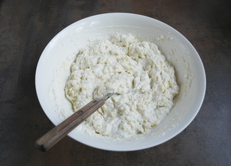 Dough for cheesecakes, spoon are in a white dish. Preparation for cooking. 