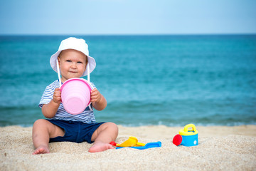 Beautiful boy playing on beach with toys and sand