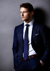 Cool businessman standing on grey 