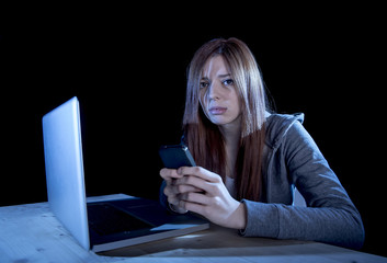 worried teenager using mobile phone and computer as internet cyber bullying stalked victim abused