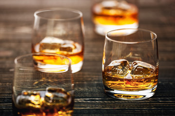 Glass of scotch whiskey and ice on a black wooden background,sel