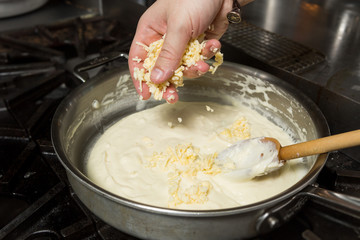 Cheese being added into a hot pan, to melt in preparation for Macaroni cheese