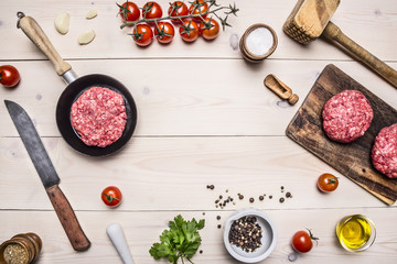 Fototapeta na wymiar cooking burgers, ground beef with herbs and cherry tomatoes on a branch border ,place for text on wooden rustic background top view