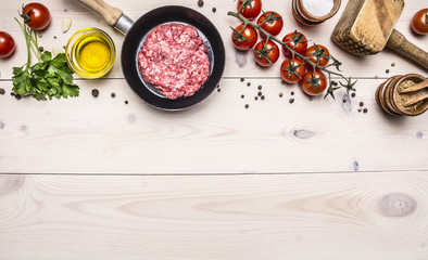 cooking burgers, ground beef with herbs and cherry tomatoes on a branch border ,place for text  on wooden rustic background top view
