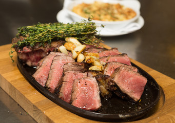 A selection of grilledT Bone steak pieces roasted garlic and rosemary, off the bone on a metal plate